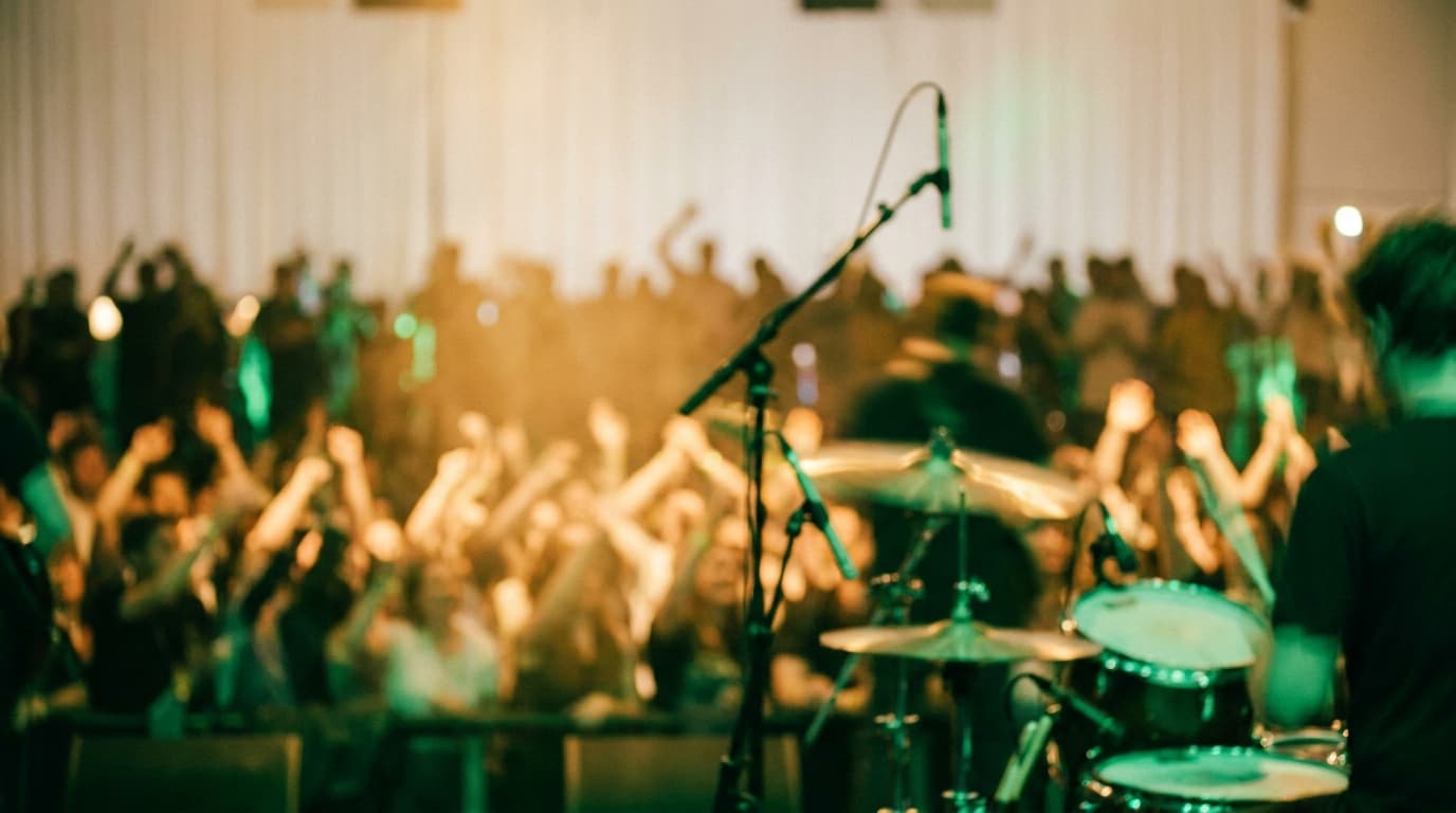 A performer's-eye view from the stage of a lively, warmly lit crowd at night with soft motion